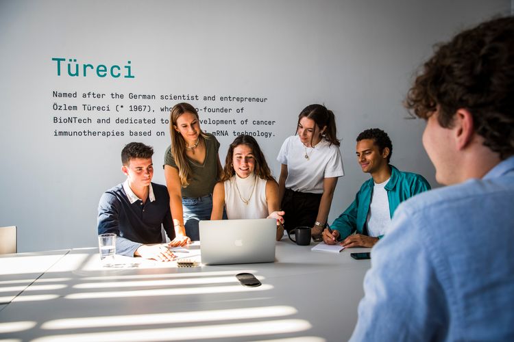 A group of students is looking on a laptop